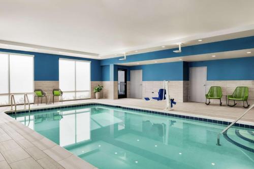 奥利安Hampton Inn & Suites Olean, Ny的游泳池拥有蓝色的墙壁和绿色的椅子