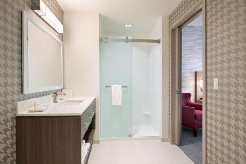 埃文代尔Home2 Suites By Hilton Phoenix Avondale, Az的浴室配有盥洗盆和带镜子的淋浴