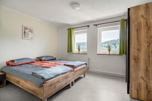 苏尔Ferienwohnung Suhl/ Wichtshausen的一间卧室设有一张床和两个窗户。