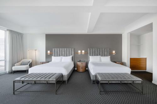 爱荷华Hotel Chauncey Iowa City, Tapestry Collection by Hilton的酒店客房,配有两张床和椅子