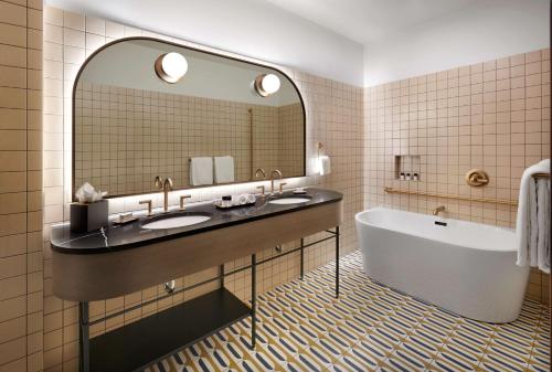 卡尔加里The Westley Calgary Downtown, Tapestry Collection By Hilton的浴室设有2个水槽、浴缸和镜子