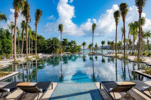 图卢姆Conrad Tulum Riviera Maya的一座棕榈树和椅子的游泳池