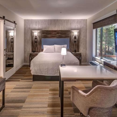 南太浩湖Hampton Inn & Suites South Lake Tahoe的卧室配有一张床和一张桌子及椅子