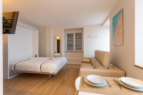 蒙达卡Apartamentos&Spa Mundaka Port的一间卧室配有一张床、一张沙发和一张桌子
