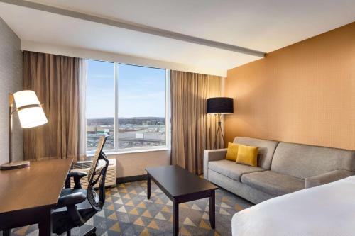 潘特克莱尔Doubletree By Hilton Pointe Claire Montreal Airport West的酒店客房配有一张床、一张沙发和一张书桌。