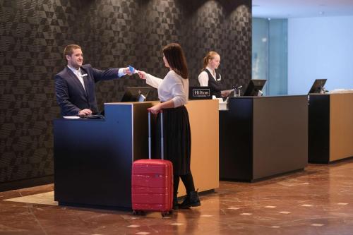 汉诺威DoubleTree by Hilton Hannover Schweizerhof的男人和女人在办公室里摇手