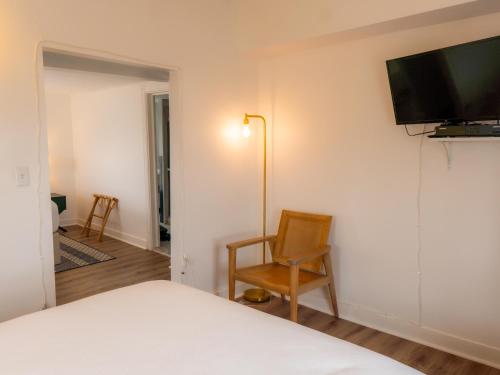 欧申格罗夫Beachliner Hotel的一间卧室配有一张床和一把椅子,墙上配有电视。