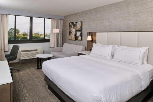 博伟公园Doubletree by Hilton Buena Park的酒店客房带一张大床和一把椅子