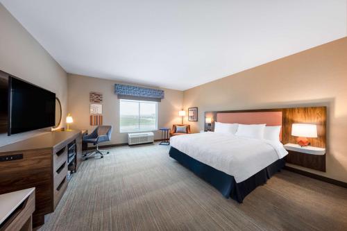 堪萨斯城Hampton Inn Kansas City Southeast, Mo的配有一张床和一台平面电视的酒店客房