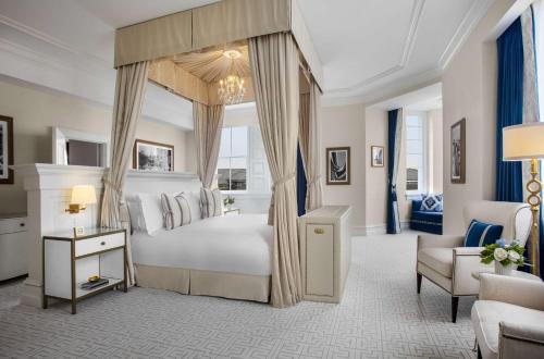 华盛顿Waldorf Astoria Washington DC的一间卧室配有一张天蓬床和一把椅子