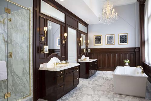 华盛顿Waldorf Astoria Washington DC的浴室配有2个盥洗盆、浴缸和淋浴。