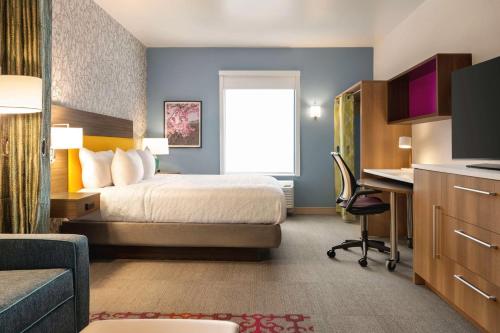 科罗拉多斯普林斯Home2 Suites By Hilton Colorado Springs I-25 Central的配有一张床和一张书桌的酒店客房