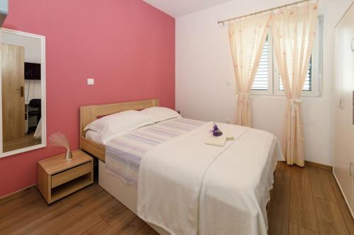 马卡尔斯卡Blue home的卧室配有白色的床和粉红色的墙壁