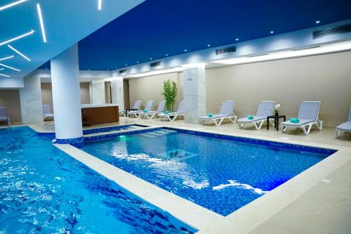 地拉那Doanesia Premium Hotel & Spa的游泳池位于酒店房间,周围设有椅子