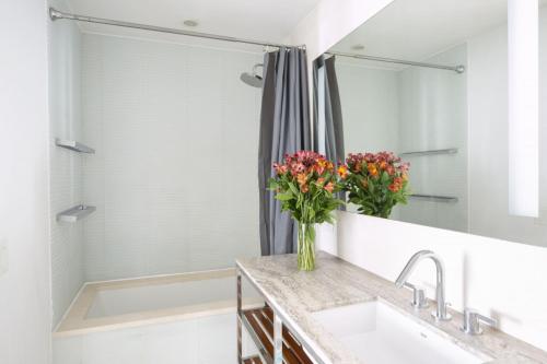 纽约Modern 2BD in Midtown with Washer and Dryer in-unit的浴室配有水槽和鲜花淋浴