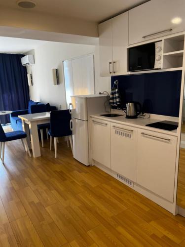 巴统Orbi City Hotel Apartments的厨房配有白色橱柜和一张带蓝色椅子的桌子。