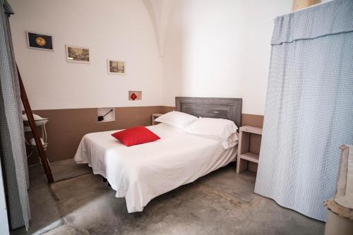 奥斯图尼Casa Le Mura的卧室配有白色的床和红色枕头