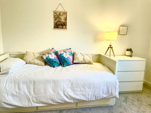 纽基Modern chic summer holiday retreat.的卧室配有带枕头和梳妆台的白色床。