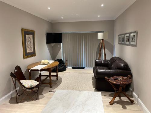 乔治Metanoia Kingswood Golf Estate的客厅配有黑色真皮沙发和桌子