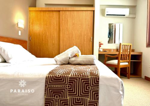 特鲁希略Hoteles Paraiso TRUJILLO的一间卧室配有一张床、一张桌子和一把椅子