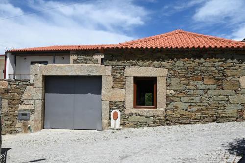 维拉·雷阿尔Casa de Trás-o-Muro的一座石头建筑,设有白色车库门