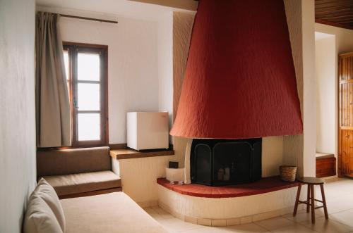 帕莱斯潘蒂雷蒙Pliades Traditional Guesthouse的客厅设有壁炉,拥有红色屋顶