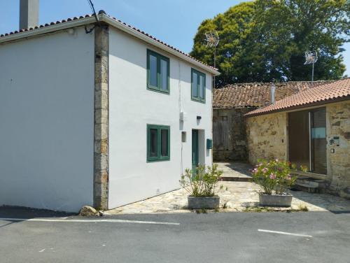 卢戈Casa Aldea de Abaixo的白色的房子,设有绿色的窗户和车库