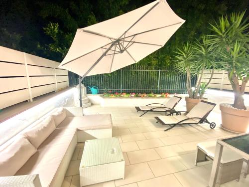 特罗佩阿Mottola Apartment的庭院配有白色沙发和遮阳伞。