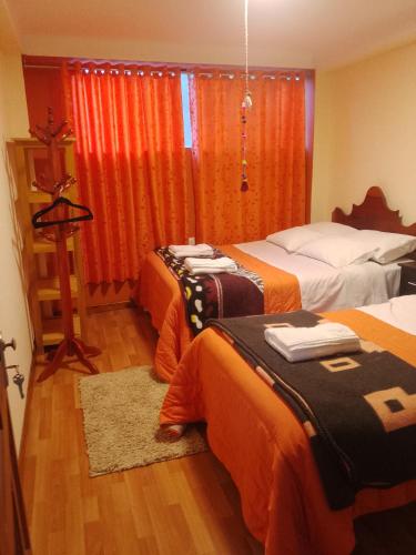 奥兰太坦波hostal ollantaytambo apartments的酒店客房带两张带橙色床单的床
