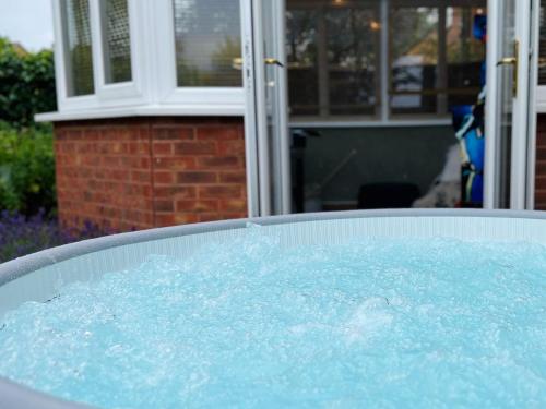 Churchdown4-bed Cotswold getaway with hot tub & gaming room的院子里装满蓝色水的热水浴池