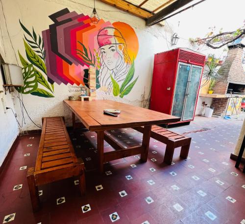 科尔多瓦Lacandona Hostel的一张木桌和一张长凳,旁边是墙上,画着绘画