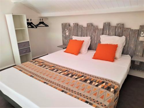 圣弗朗索瓦Gîte Cannelle的卧室内的两张床和橙色枕头