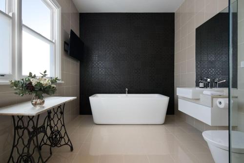 赫本温泉Barwidgee的浴室配有大型白色浴缸和水槽