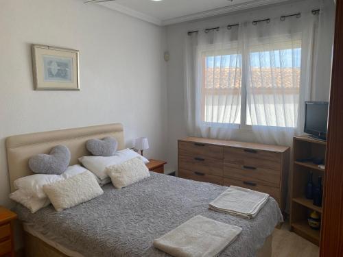 奥里韦拉海滩Luxurious 2 bedroom apartment near Cabo Roig strip的一间卧室配有带两个枕头的床和窗户