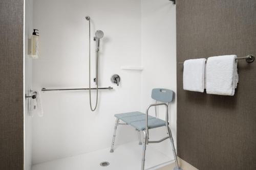 欧弗兰帕克 春季山丘套房酒店 - 堪萨斯市欧弗兰帕克的浴室内配有蓝色椅子和淋浴