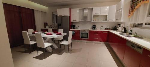 拉多斯VILA KATERINA'S的厨房配有红色橱柜和白色的桌椅
