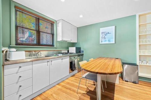 悉尼Old Sydney Comfort Self- Catering的厨房铺有木地板,配有木桌。
