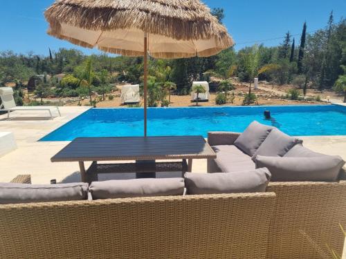 阿尔戈什Villa das Alfarrobas Cosy Guest House的游泳池旁配有桌椅和遮阳伞
