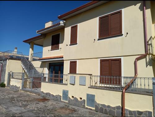 特雷斯努拉吉斯Appartamento Stelle e Coralli的白色的房子,设有棕色百叶窗和楼梯