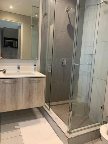 比勒陀利亚Entire Studio Apartment @MenlynMaine的一间带玻璃淋浴和水槽的浴室
