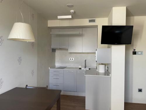 蓬费拉达Guiana Rooms - Adults Only的厨房配有白色橱柜、桌子和电视。