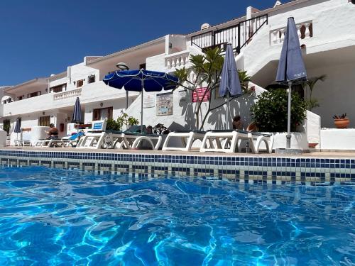 El GuinchoCoral Bay Port Royale的酒店旁的游泳池配有椅子和遮阳伞