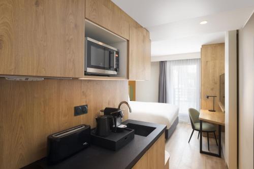 巴黎Residence Inn by Marriott Paris Didot Montparnasse的酒店客房配有一张床和一间带微波炉的厨房