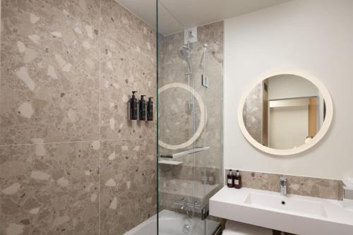 巴黎Residence Inn by Marriott Paris Didot Montparnasse的带淋浴、盥洗盆和镜子的浴室