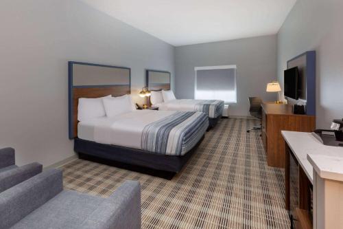 芒廷霍姆AmericInn by Wyndham Mountain Home的酒店客房设有两张床和电视。