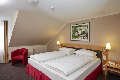 腓特烈罗达腓特烈罗达H+水疗酒店的酒店客房,配有一张床和一张红色椅子