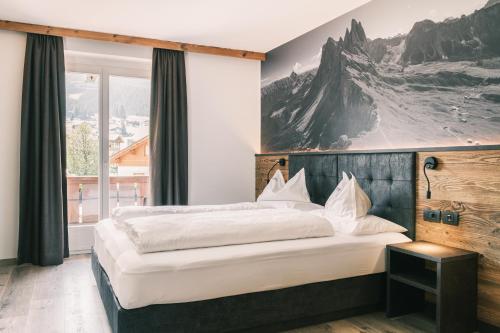 塞尔瓦迪加尔代纳山谷Kristiania Small Dolomites Hotel的一间卧室设有一张大床和一个大窗户