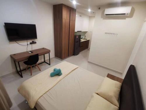 古晋Kuching Kozi Square Apartment (II)的客房设有床、书桌和电视。