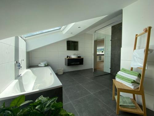 基姆高地区阿绍Alpenland Apartments的带浴缸、水槽和椅子的浴室