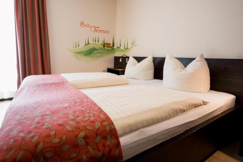 灵斯海姆Hotel La Toscana Nähe Europapark的卧室配有带白色枕头的大床